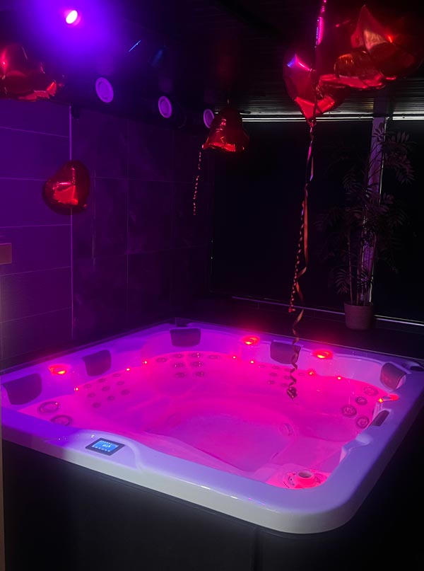 En upplyst bubbelpool med ballong-hjärtan i taket